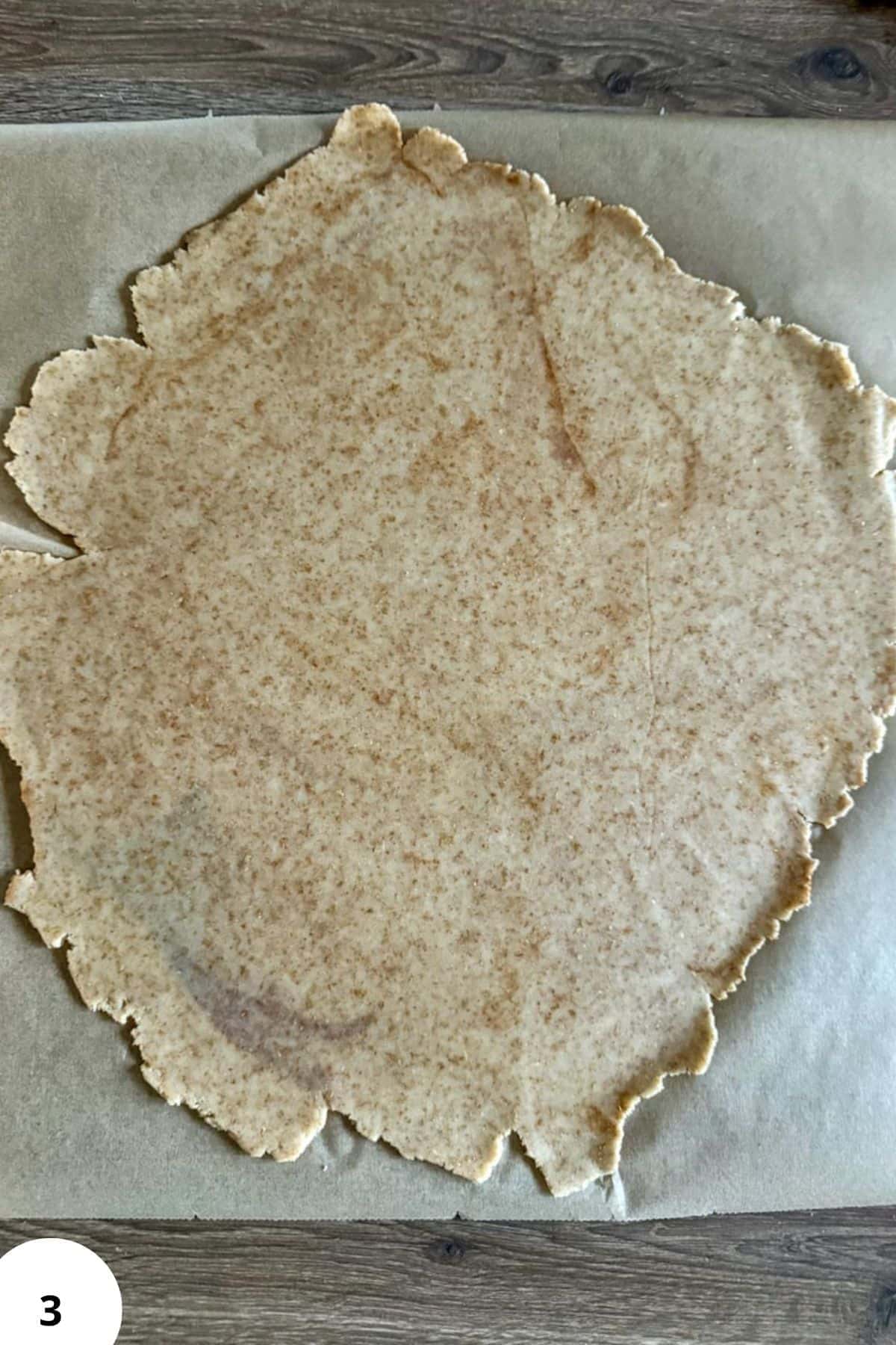 Unbaked cinnamon toast crunch cereal sheet on parchment paper.