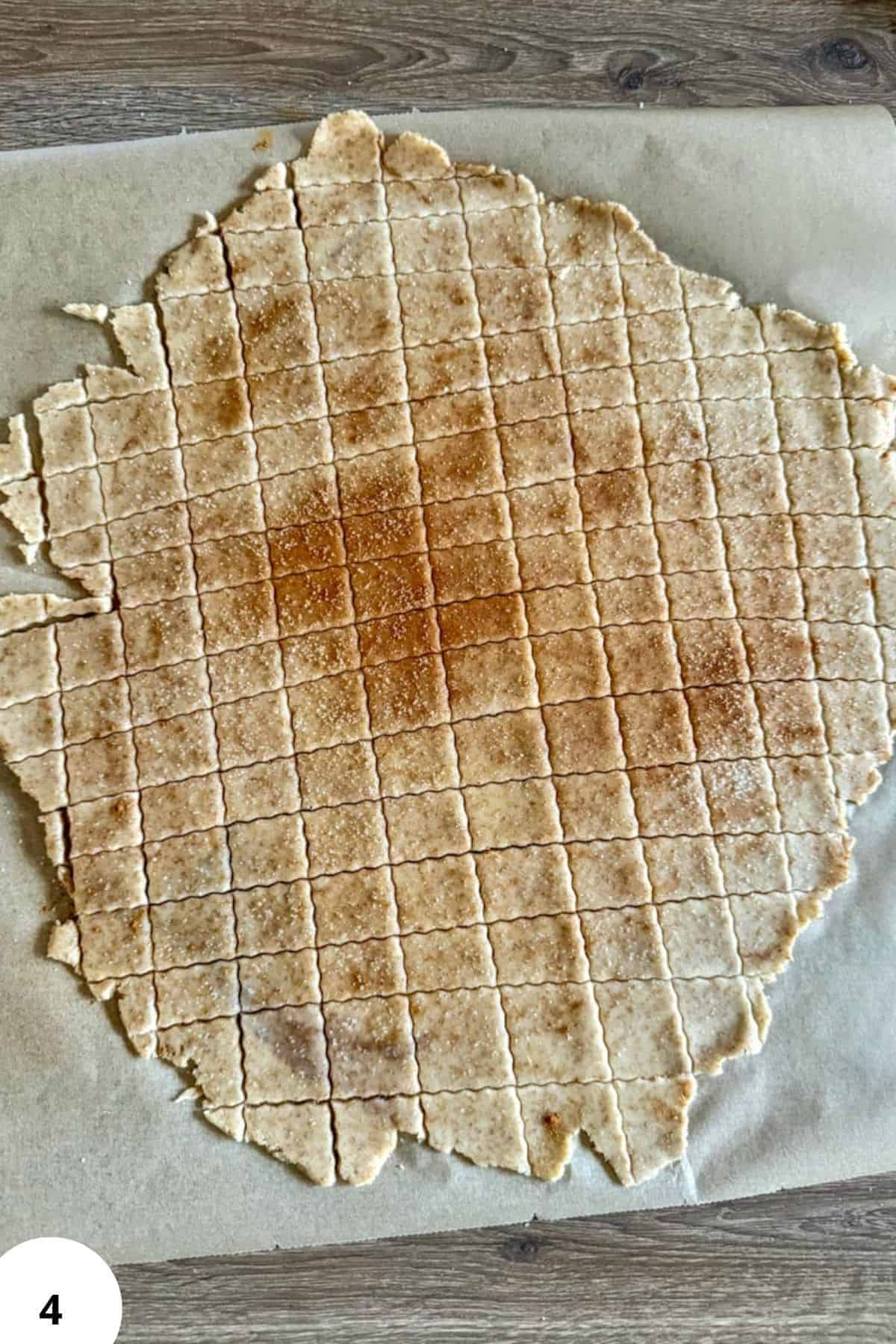 Freshly baked cinnamon cereal sheet with grid pattern on parchment paper.