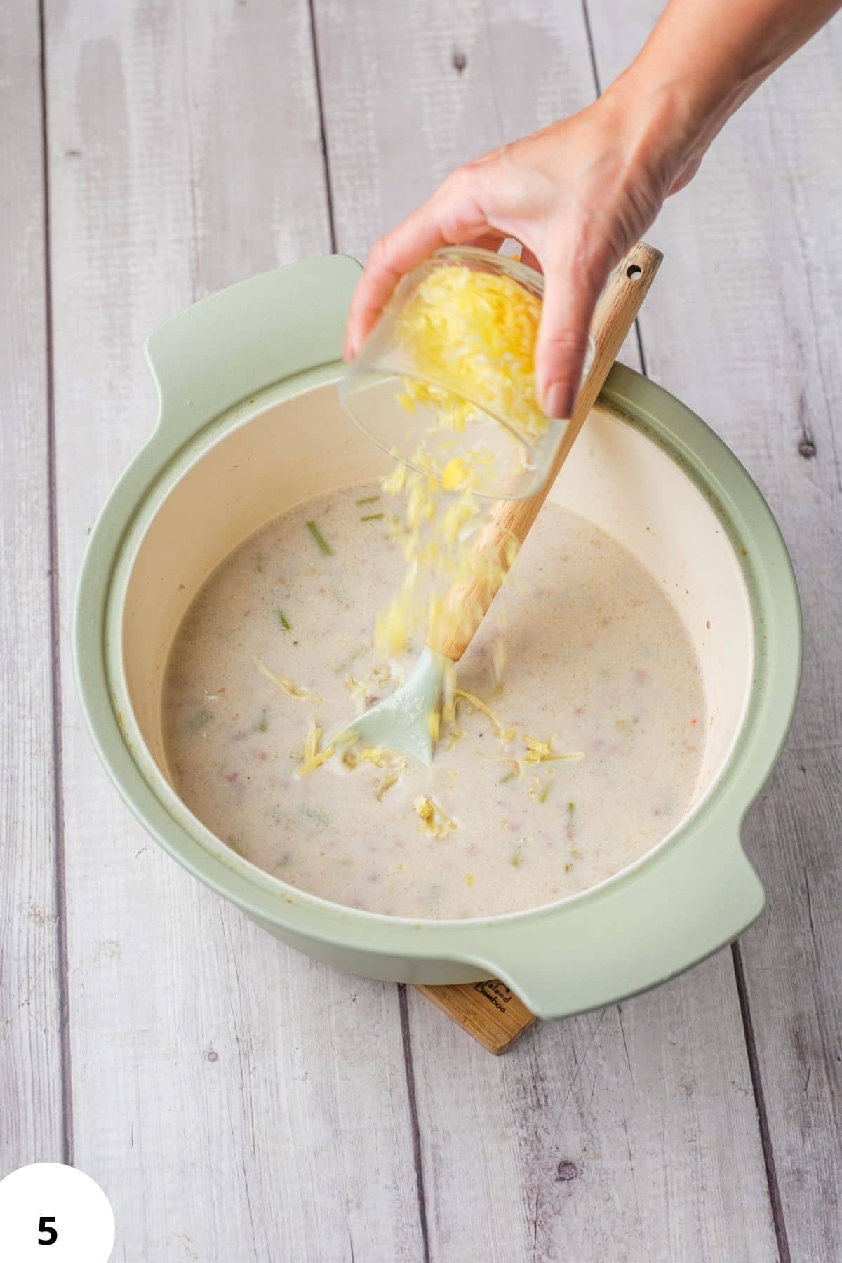 Hand performing stretch and fold technique on bread dough in a bowl.