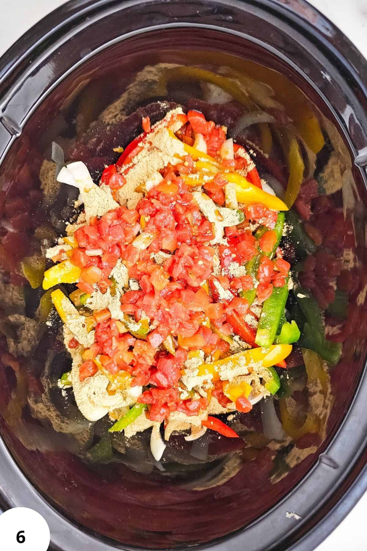 Chicken fajitas ingredients in slow cooker with peppers and tomatoes.