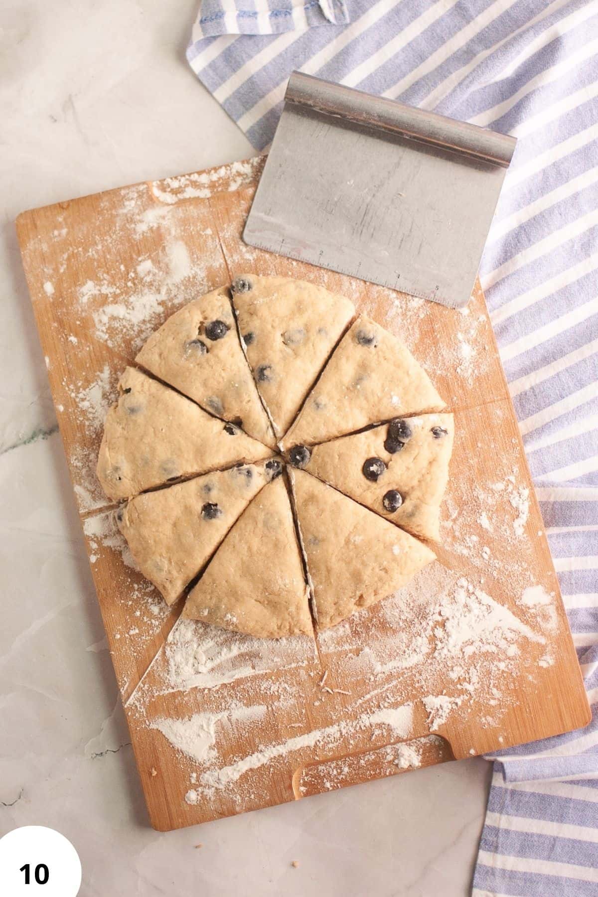 Freshly cut sourdough blueberry cream scones on a wooden board with flour dusting.