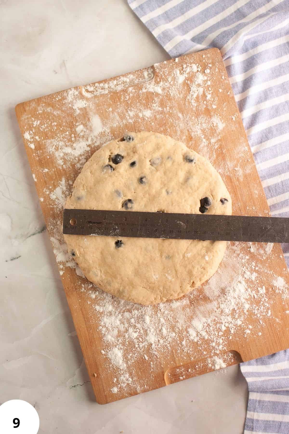 Sourdough blueberry cream scone dough on a wooden board with a ruler.
