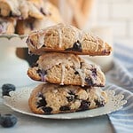 Fresh sourdough blueberry cream scones stacked on a plate, perfect for breakfast or snack.
