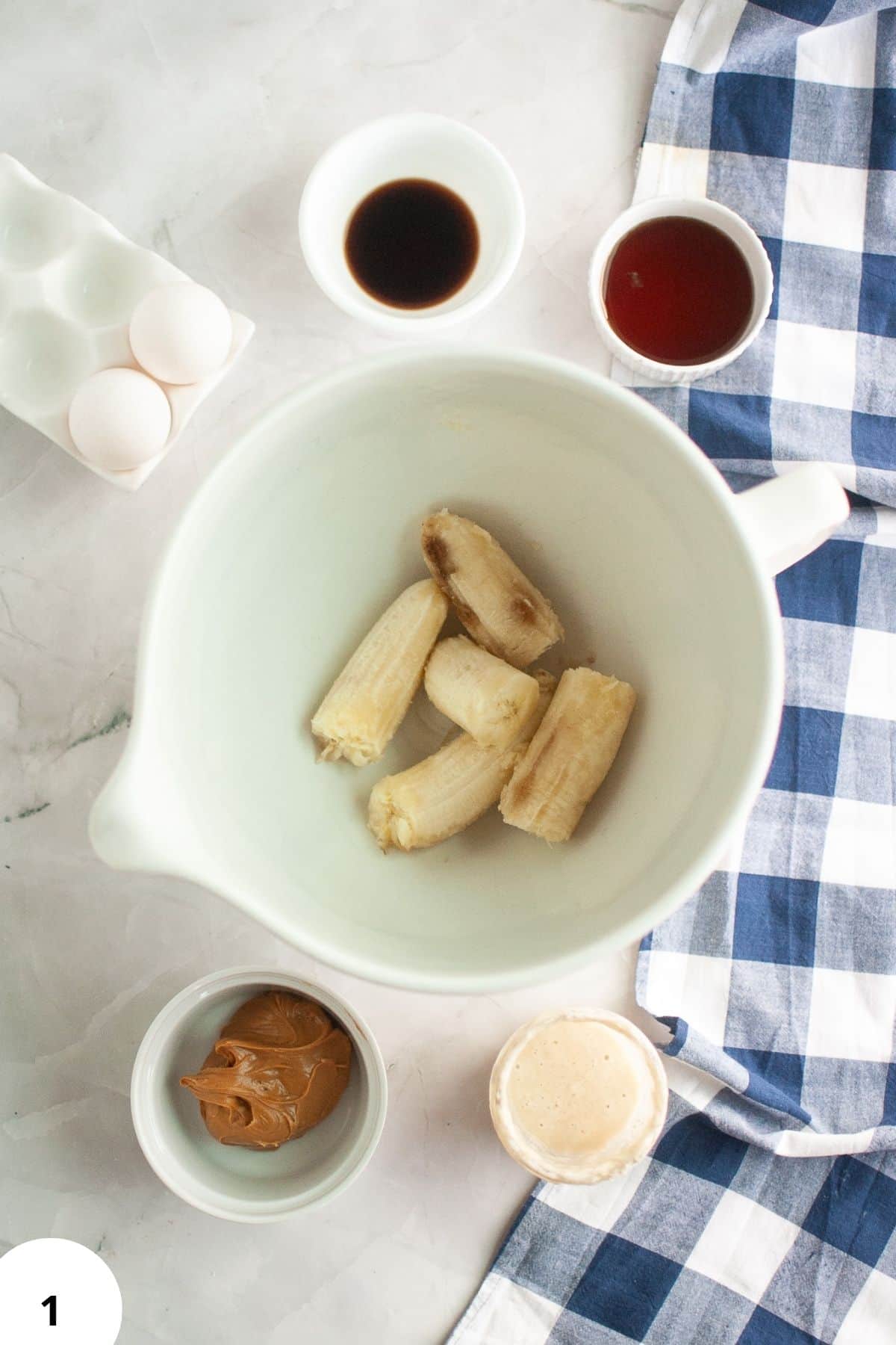 Sourdough banana muffins with chocolate chips and banana pieces in a white bowl.