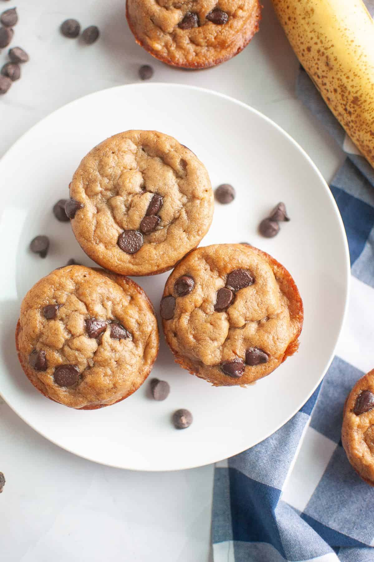 Freshly baked sourdough banana muffins with chocolate chips on a white plate.