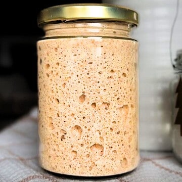 Fermentation jar with bubbly sourdough starter for baking.