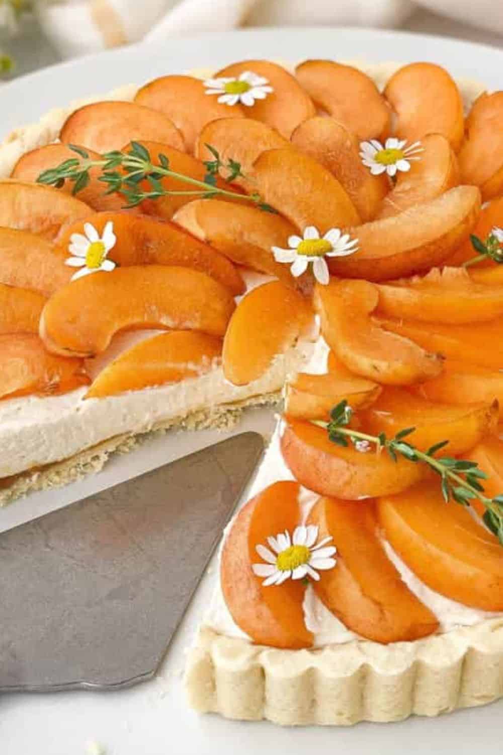 Apricot tart featuring fresh apricots and delicate edible flowers, showcasing beautiful presentation.