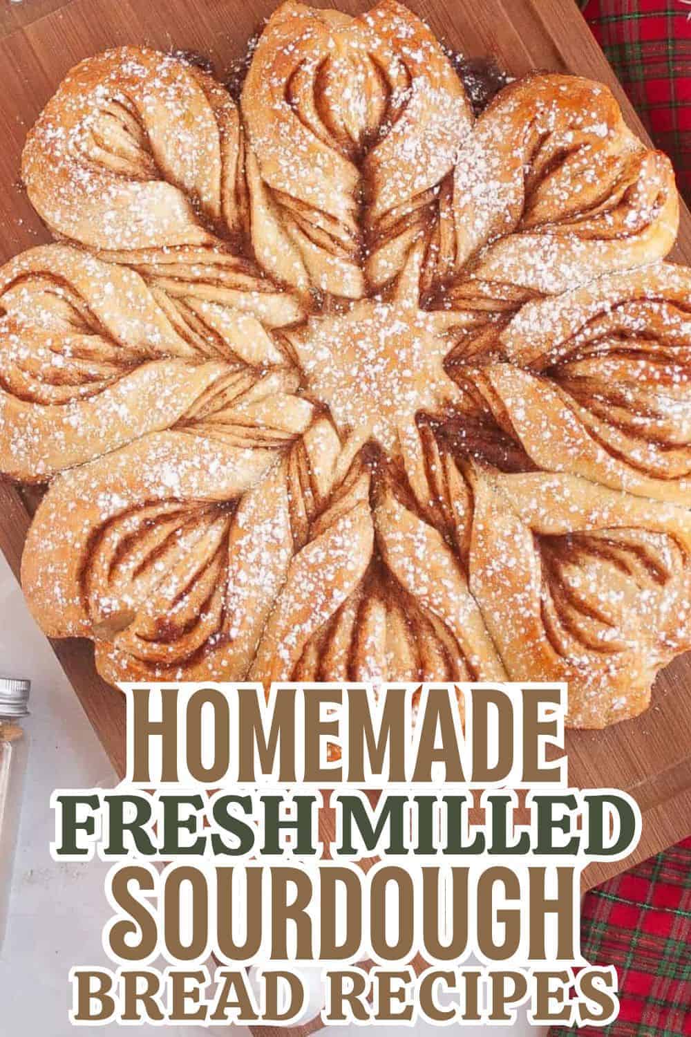 Homemade sourdough bread with intricate braided design, dusted with powdered sugar, on a wooden boar.