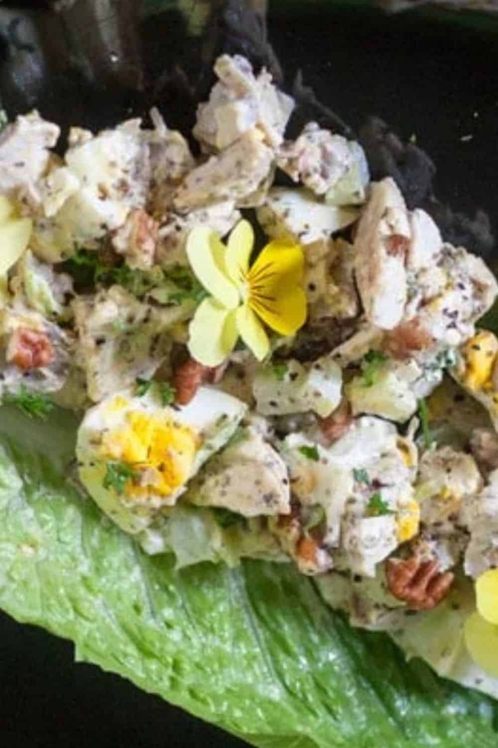 Delicious salad with chopped eggs, nuts, and fresh herbs on a lettuce leaf.