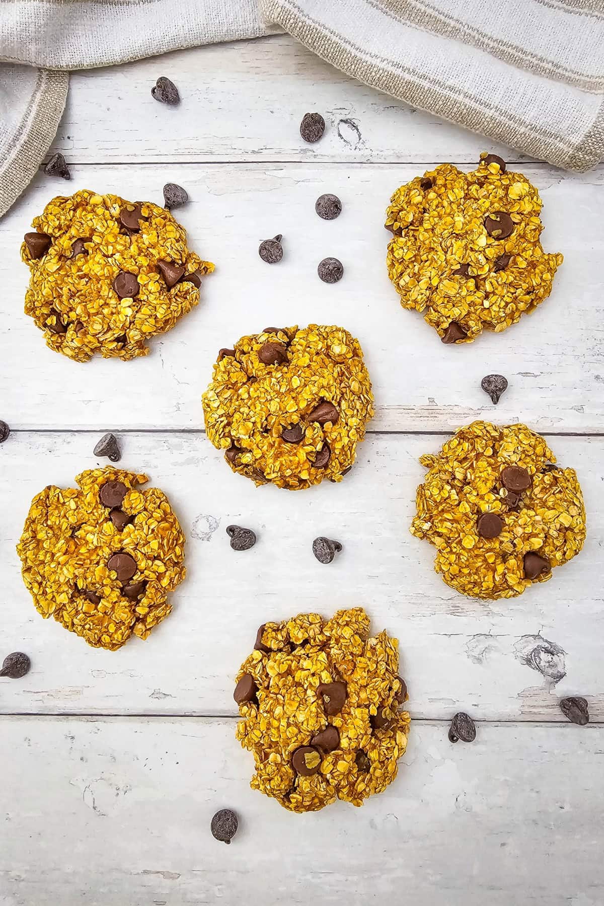 Delicious pumpkin oatmeal cookies with chocolate chips on a white wooden surface.