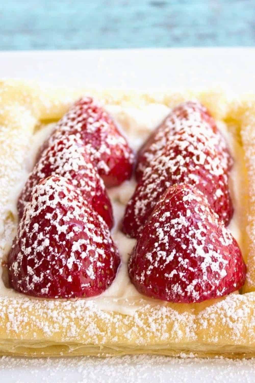 Strawberry pastry with fresh berries, powdered sugar, and cream filling.
