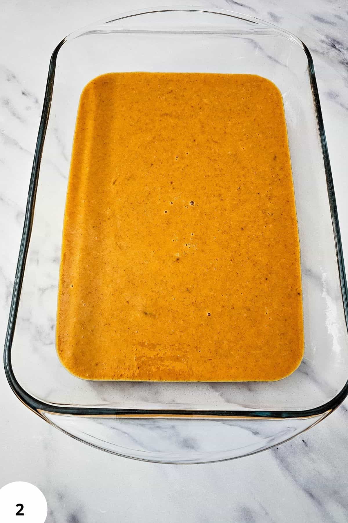 Smooth pumpkin pie filling in glass baking dish for dessert preparation.