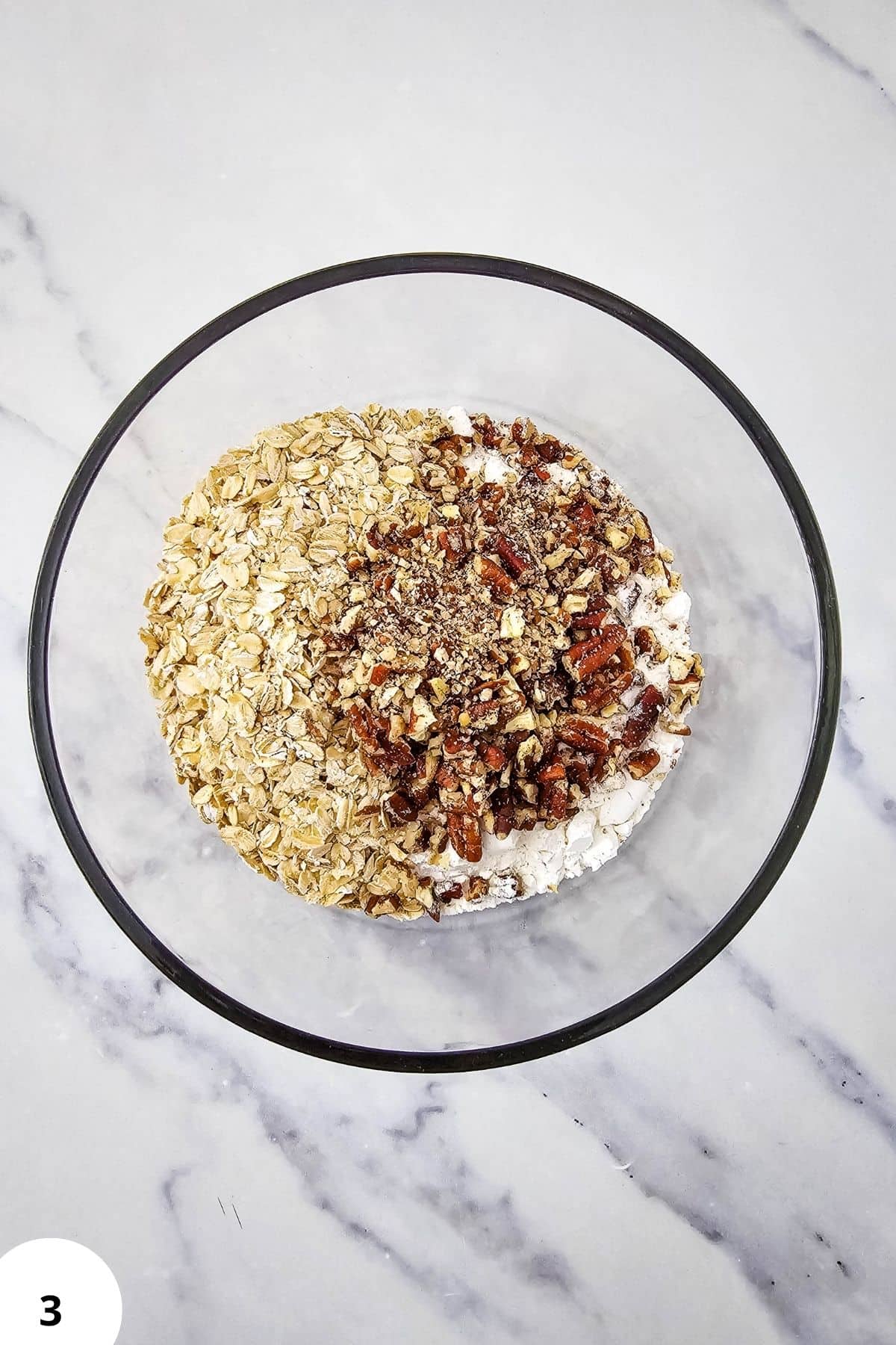 Pumpkin pie crisp ingredients with buttery pecan oat topping in a glass dish.