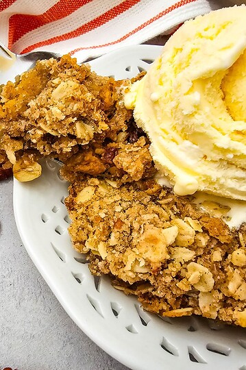 Delicious pumpkin pie crisp topped with buttery pecan oat crumble and a scoop of vanilla ice cream.
