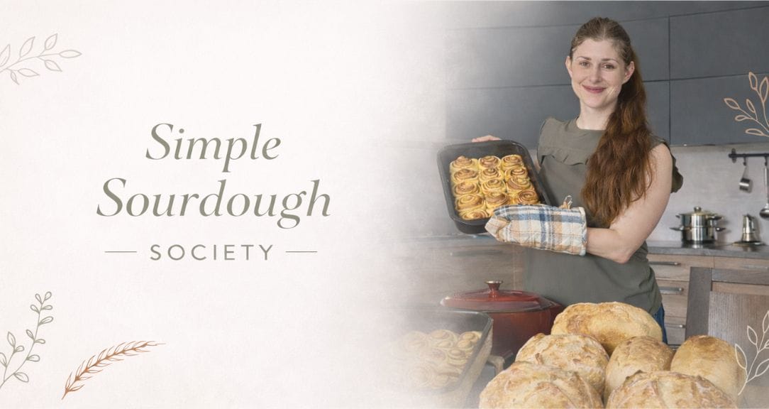 Woman holding freshly baked sourdough bread in a bakery kitchen.