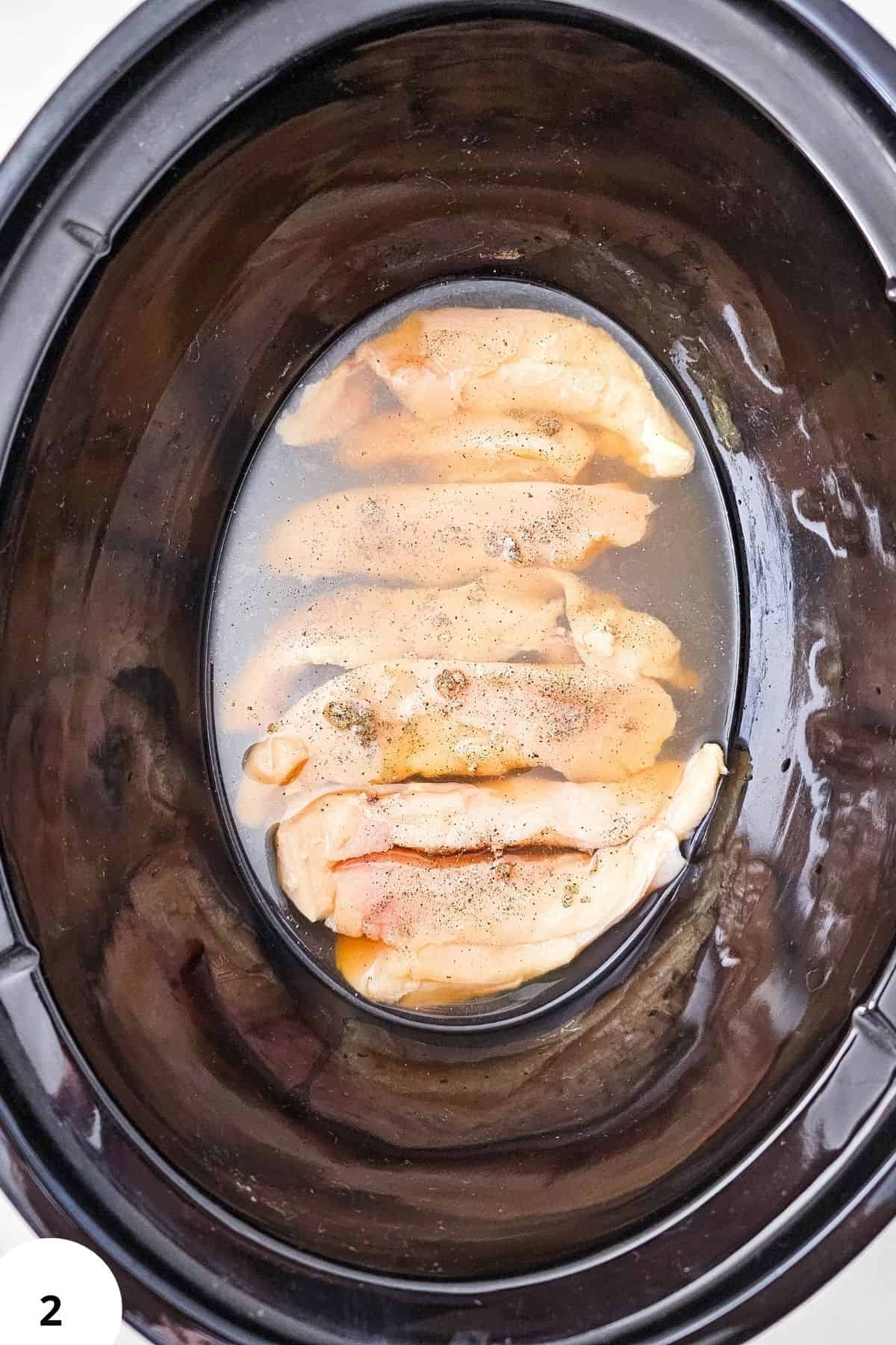 Chicken Marsala cooking in a slow cooker with mushrooms and sauce.