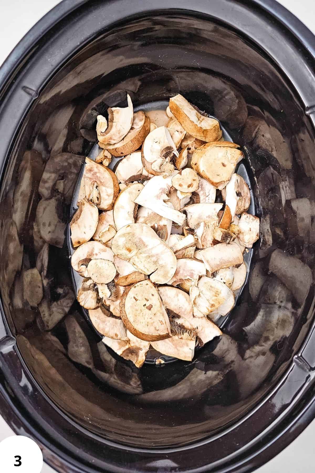 Mushrooms sliced and ready for slow cooking in a black slow cooker.