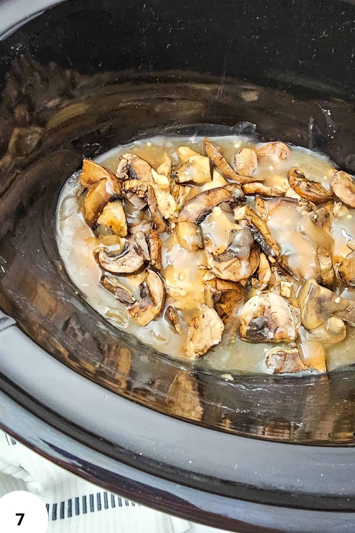 Chicken Marsala cooking in slow cooker with mushrooms and sauce.
