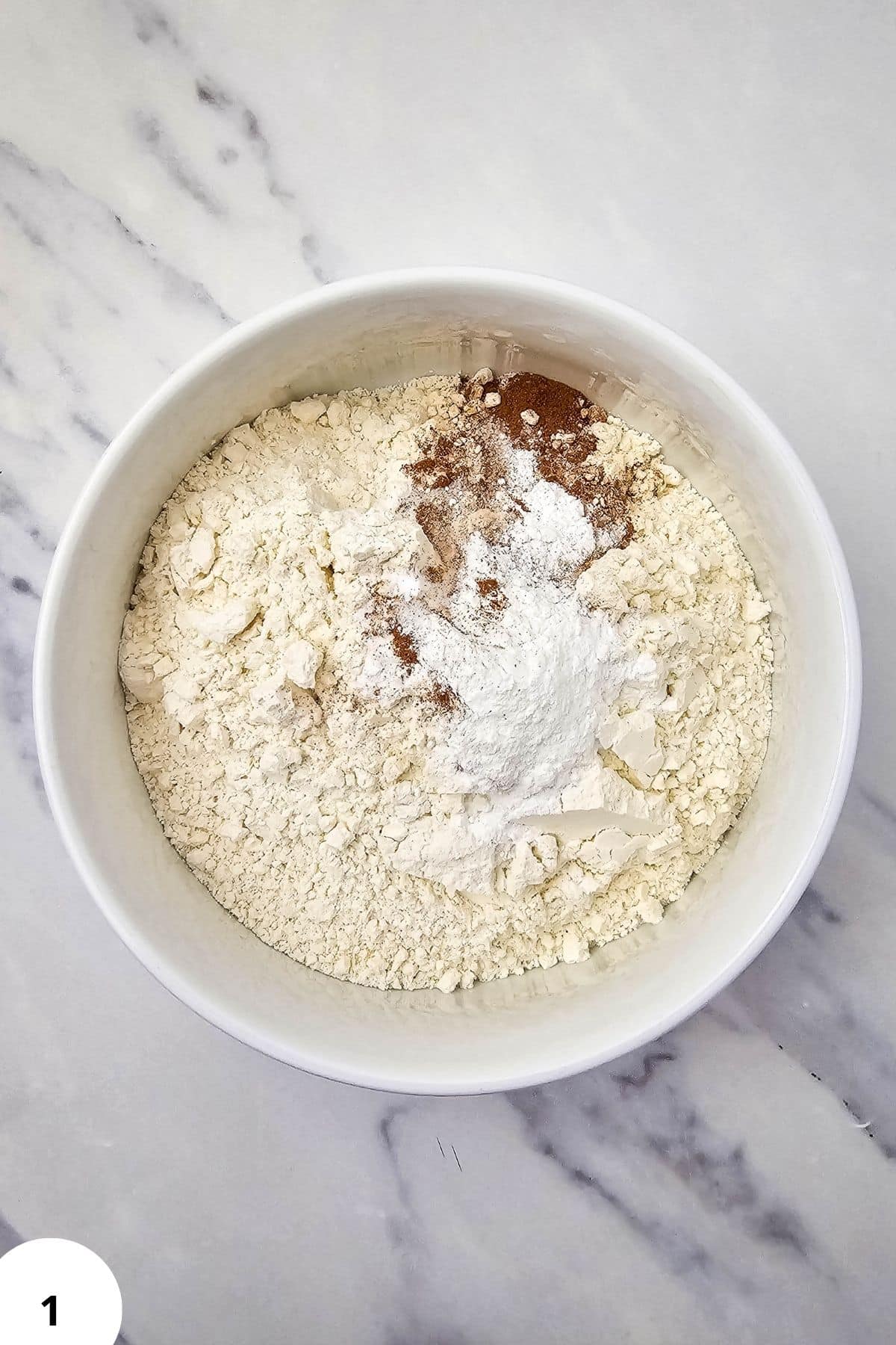 Preparing dough for blackberry muffins with streusel topping in a white bowl.