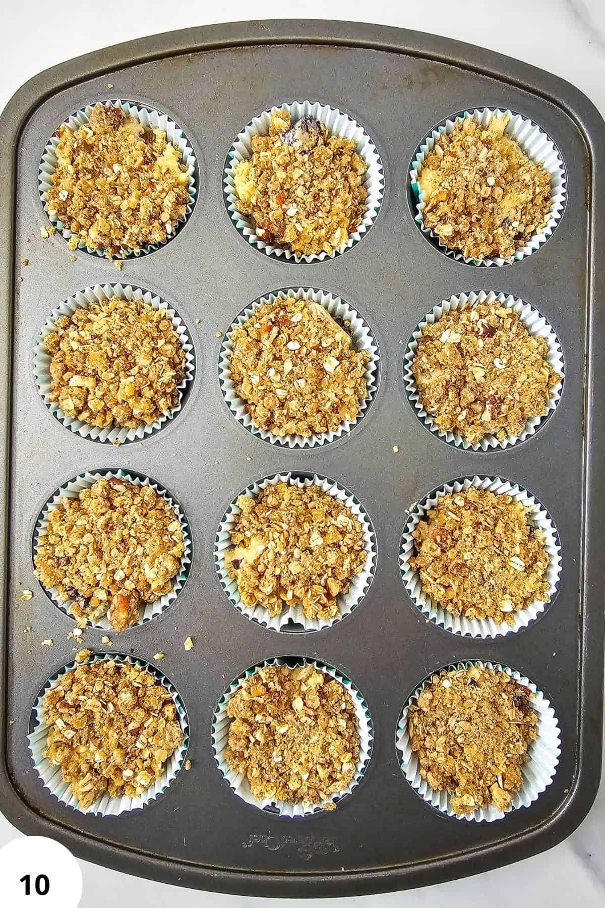 Freshly baked blackberry muffins with streusel topping in a muffin tin.