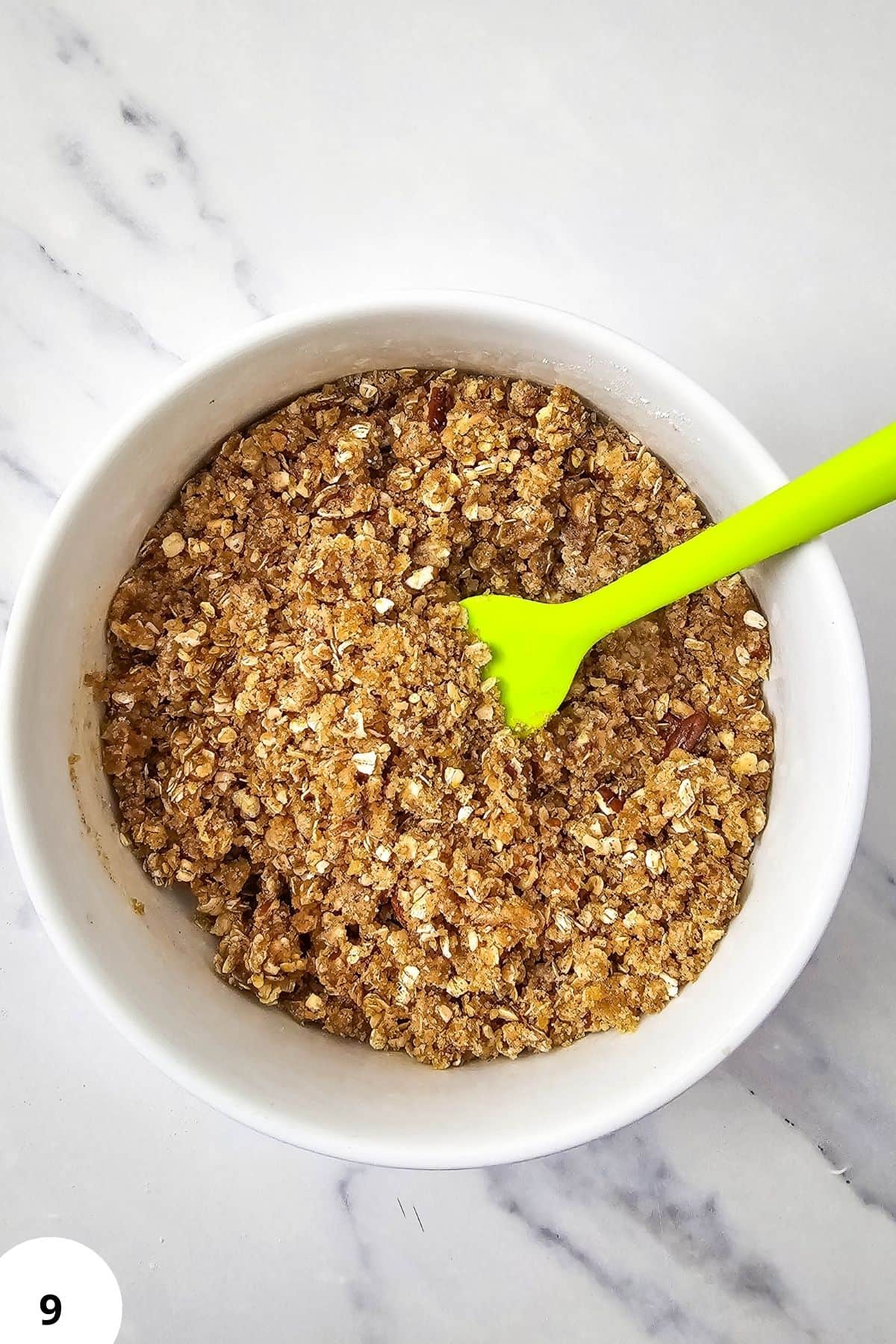 Blackberry muffin streusel topping in a white bowl with a green spoon.