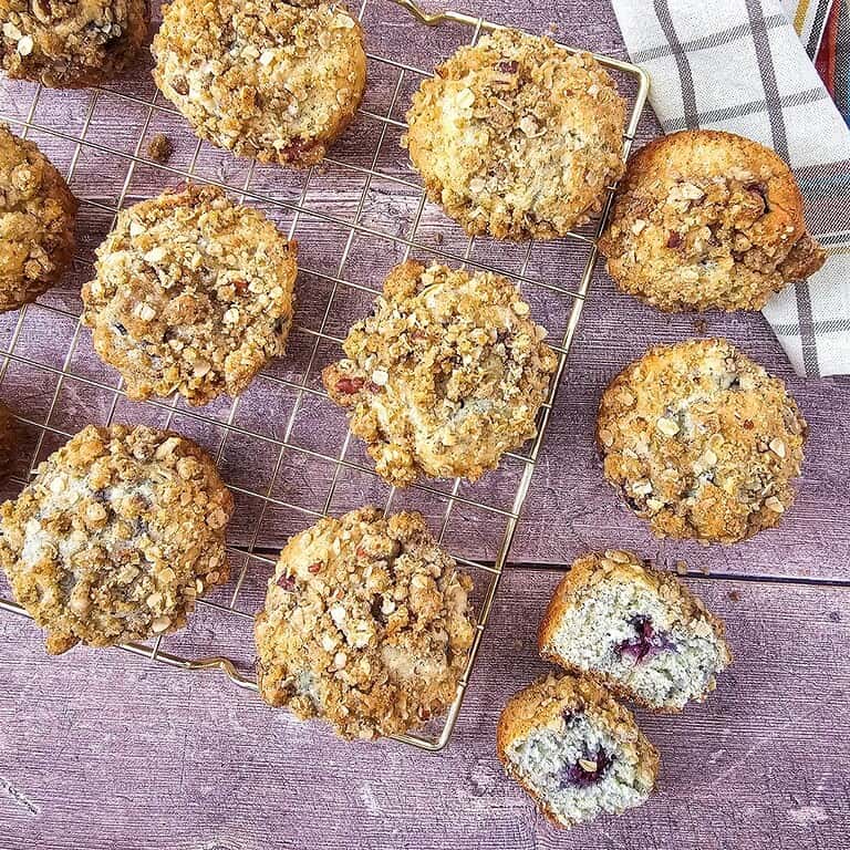 Freshly baked blackberry muffins with streusel topping on a cooling rack.