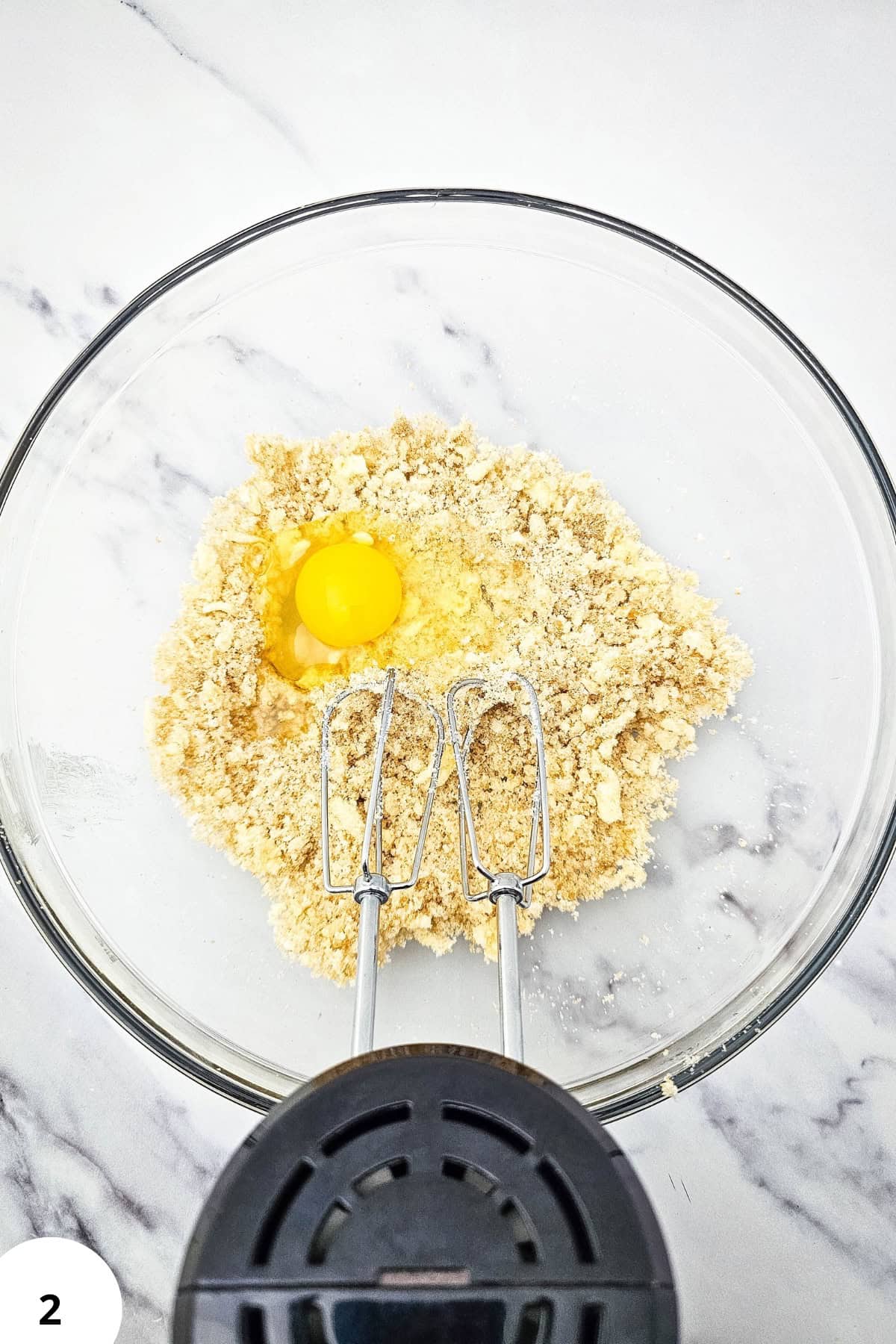 Mixing bowl with cookie dough, raisins, and egg for oatmeal raisin cookies.