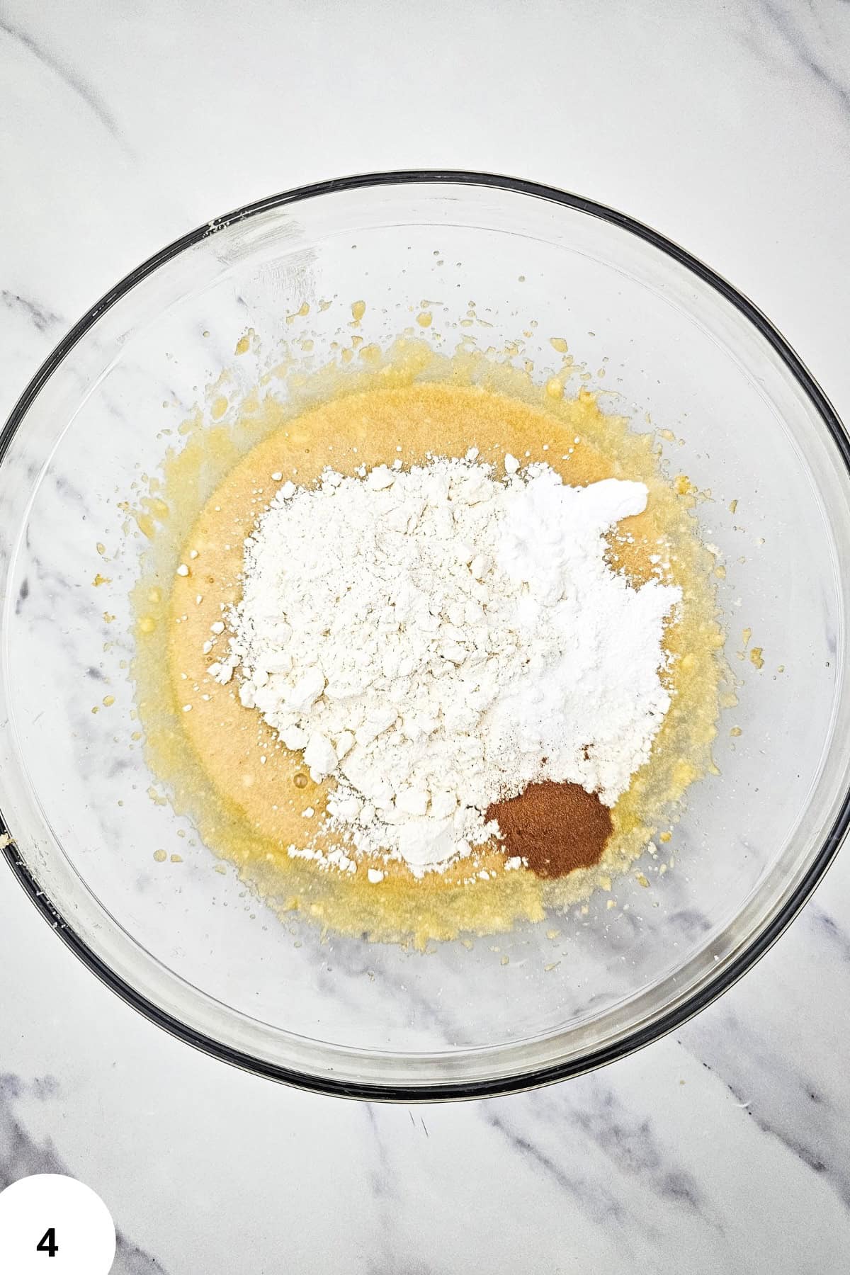 Mixing bowl with cookie dough ingredients for soft oatmeal raisin applesauce cookies.