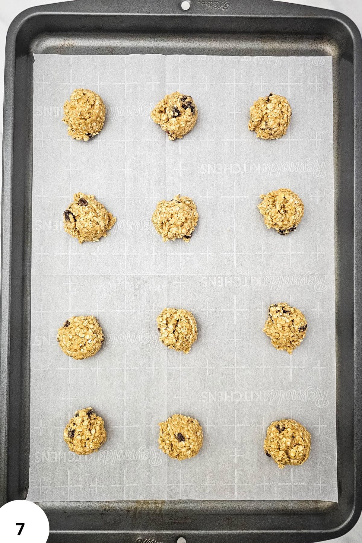 Oatmeal raisin cookies on a baking sheet, showcasing the dough's texture and ingredients.