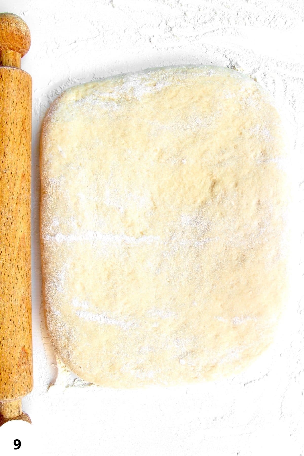 Sourdough dough being prepared for poppy seed rolls with a rolling pin.