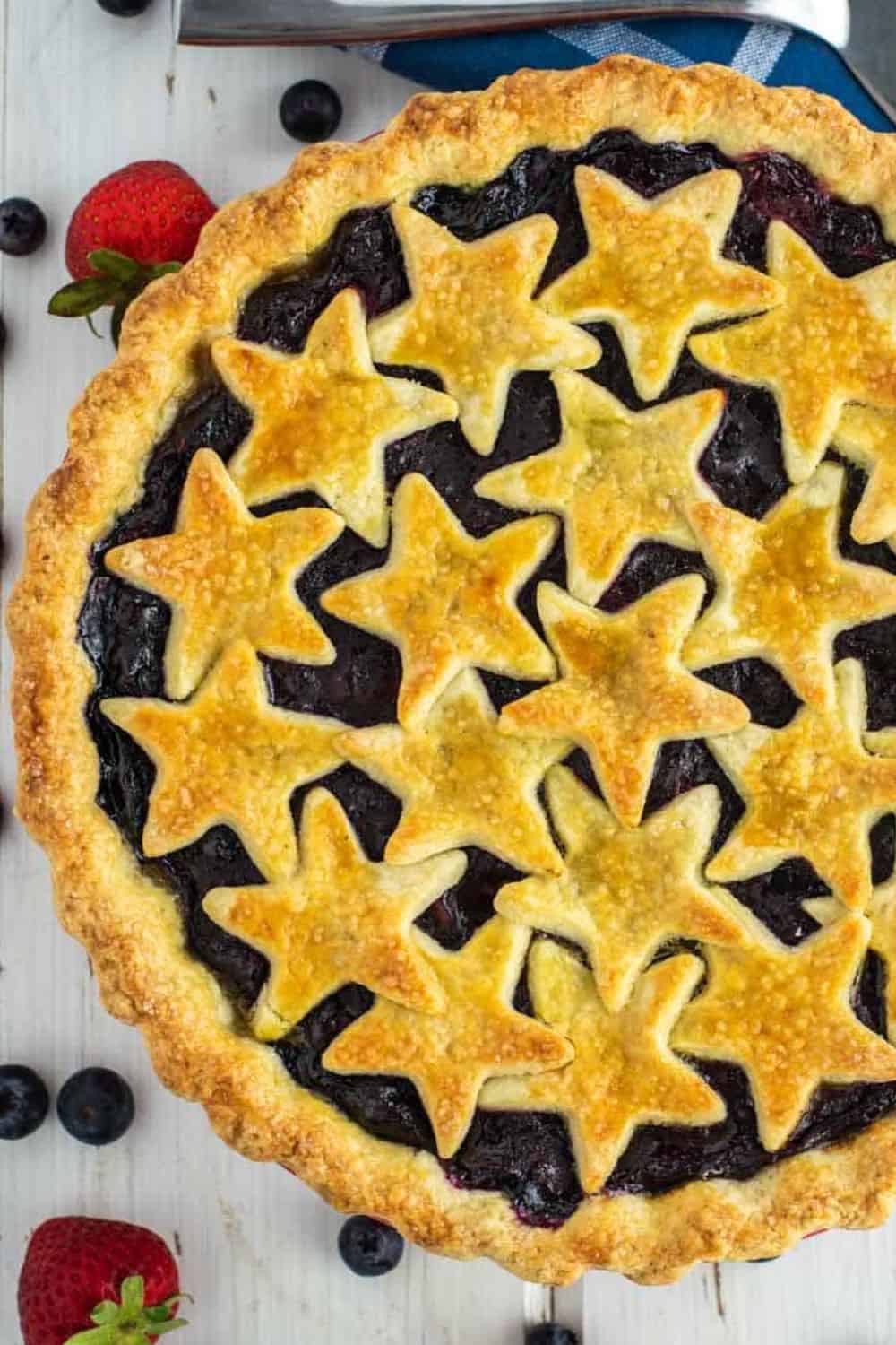 Delicious berry pie with star-shaped pastry crust, fresh berries around.