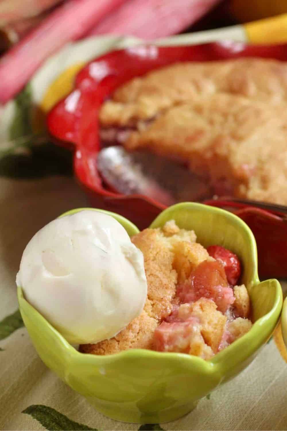 Delicious strawberry cobbler served with vanilla ice cream in a green bowl.