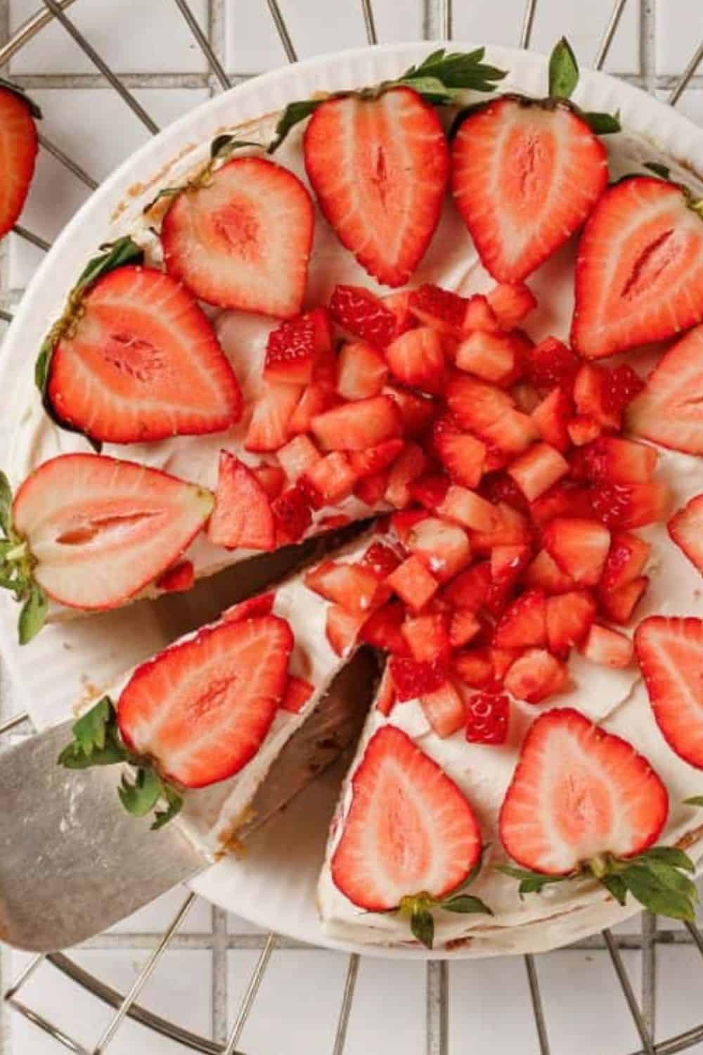 Fresh strawberry cake topped with sliced strawberries and green garnish.
