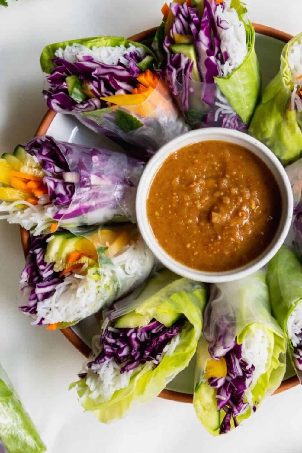 Vegetable spring rolls with vibrant purple cabbage and fresh greens, served with a tangy dipping sau.