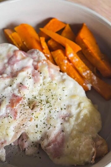 Delicious ham and cheese omelette with sweet potato fries on a white plate.
