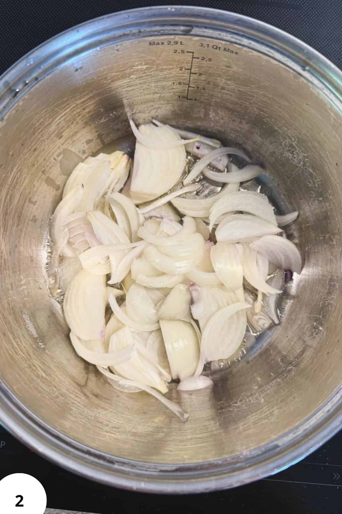 Sliced red cabbage and apple for braising, in a stainless steel pot.