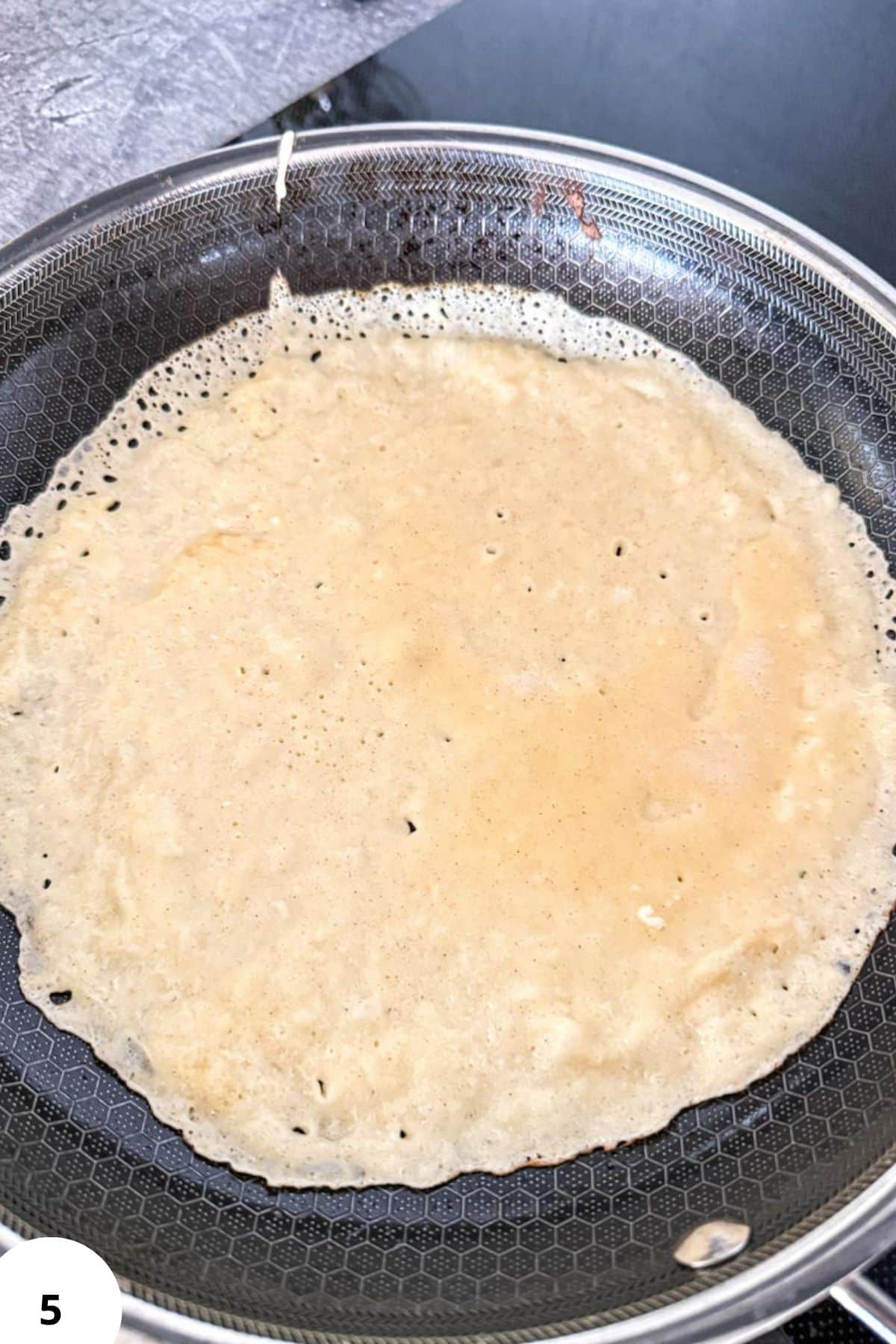 Sourdough crepe cooking in a non-stick pan, ready for filling.