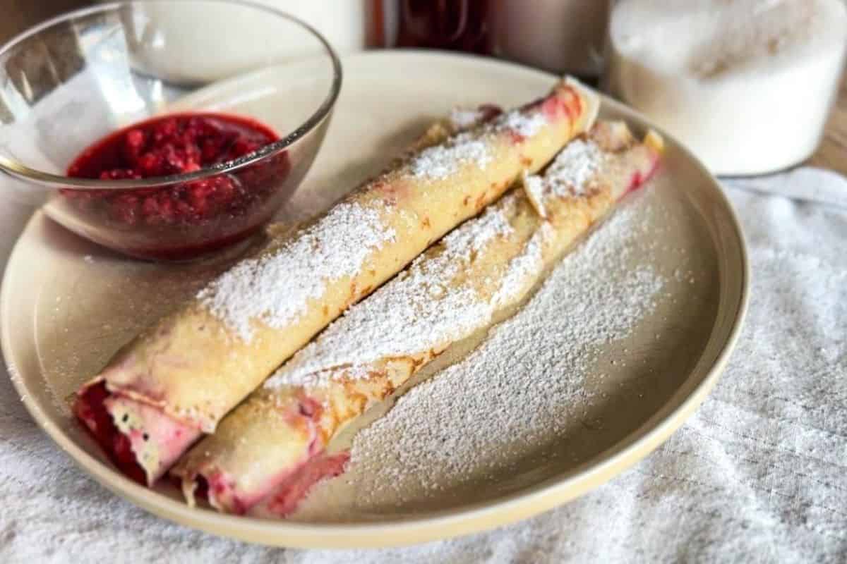 Delicious sourdough Palatschinken filled with fruit, dusted with powdered sugar, served with berry c.