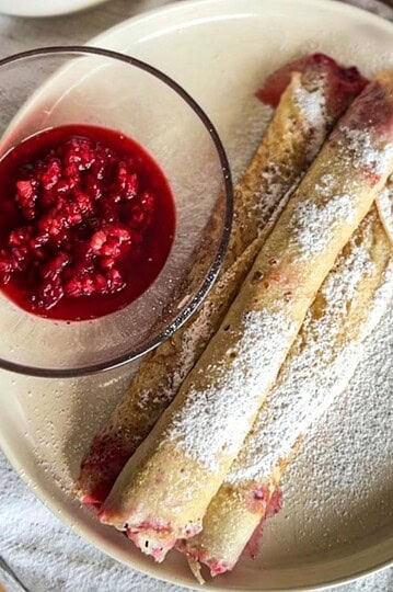 Delicious sourdough palatschinken served with fresh berry compote, dusted with powdered sugar for a.