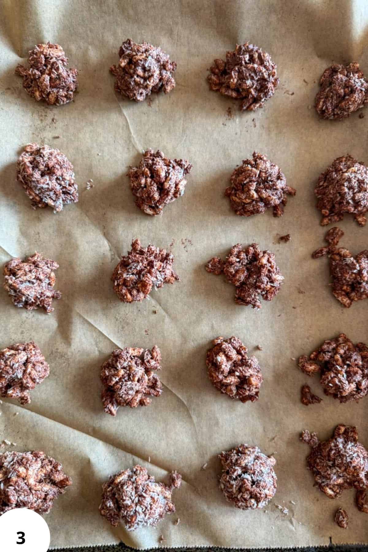 Freshly baked chocolate cookie dough clusters on parchment paper, ready for baking or cooling.