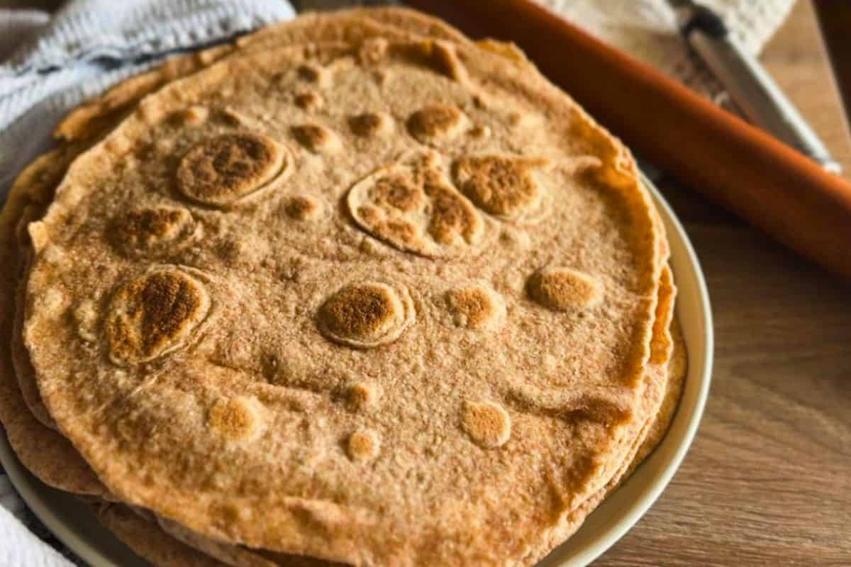Freshly baked whole grain flatbread made with freshly milled flour on a rustic wooden table.