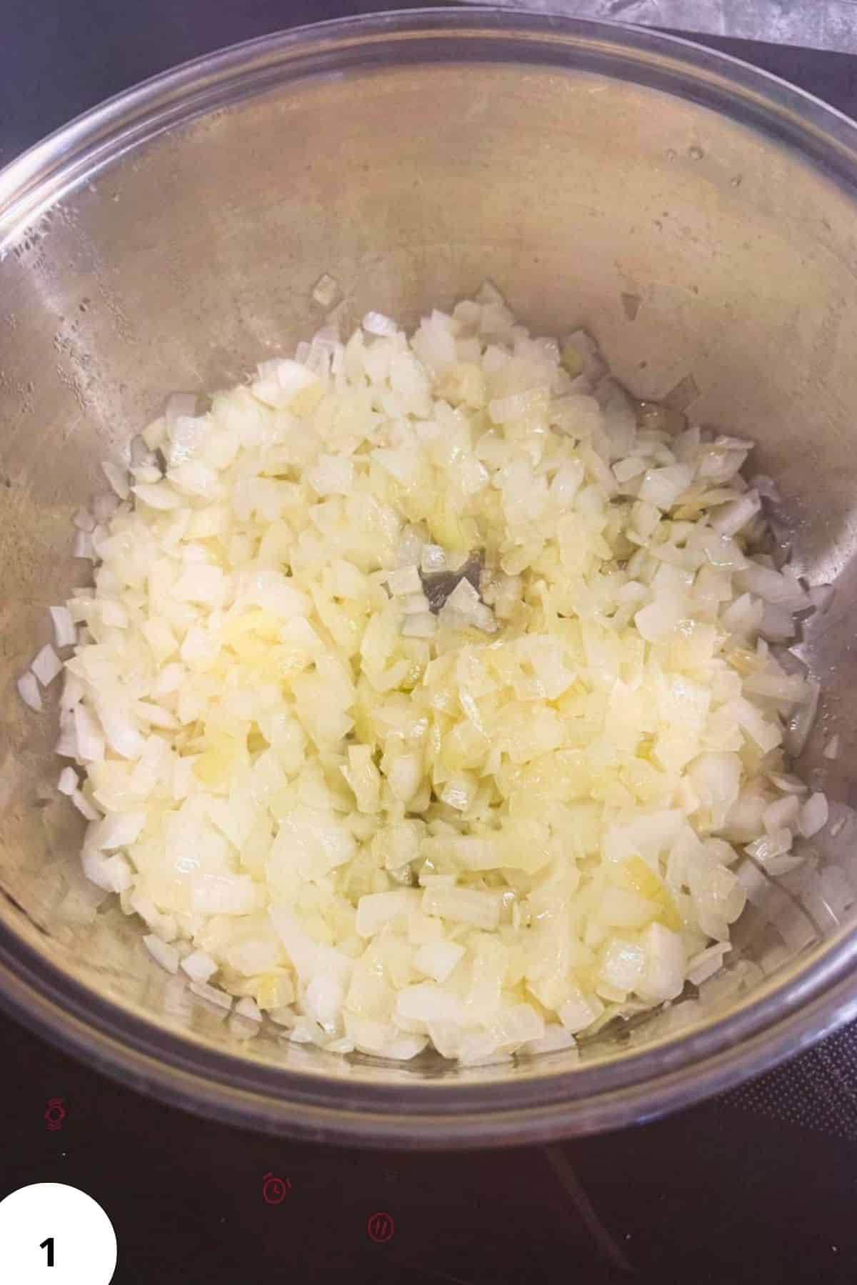 Sautéed chopped onions in a stainless steel pan, ready to enhance the flavor of Pork and Sauerkraut.