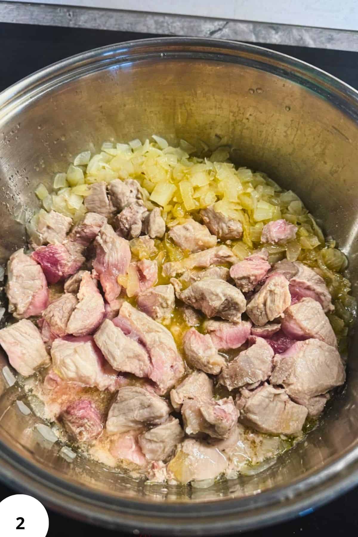 Pork and sauerkraut in a metal bowl, ready for cooking.