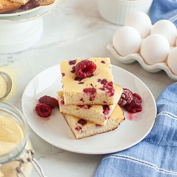 Raspberry cake slices with fresh berries on a white plate, perfect for dessert or tea time.