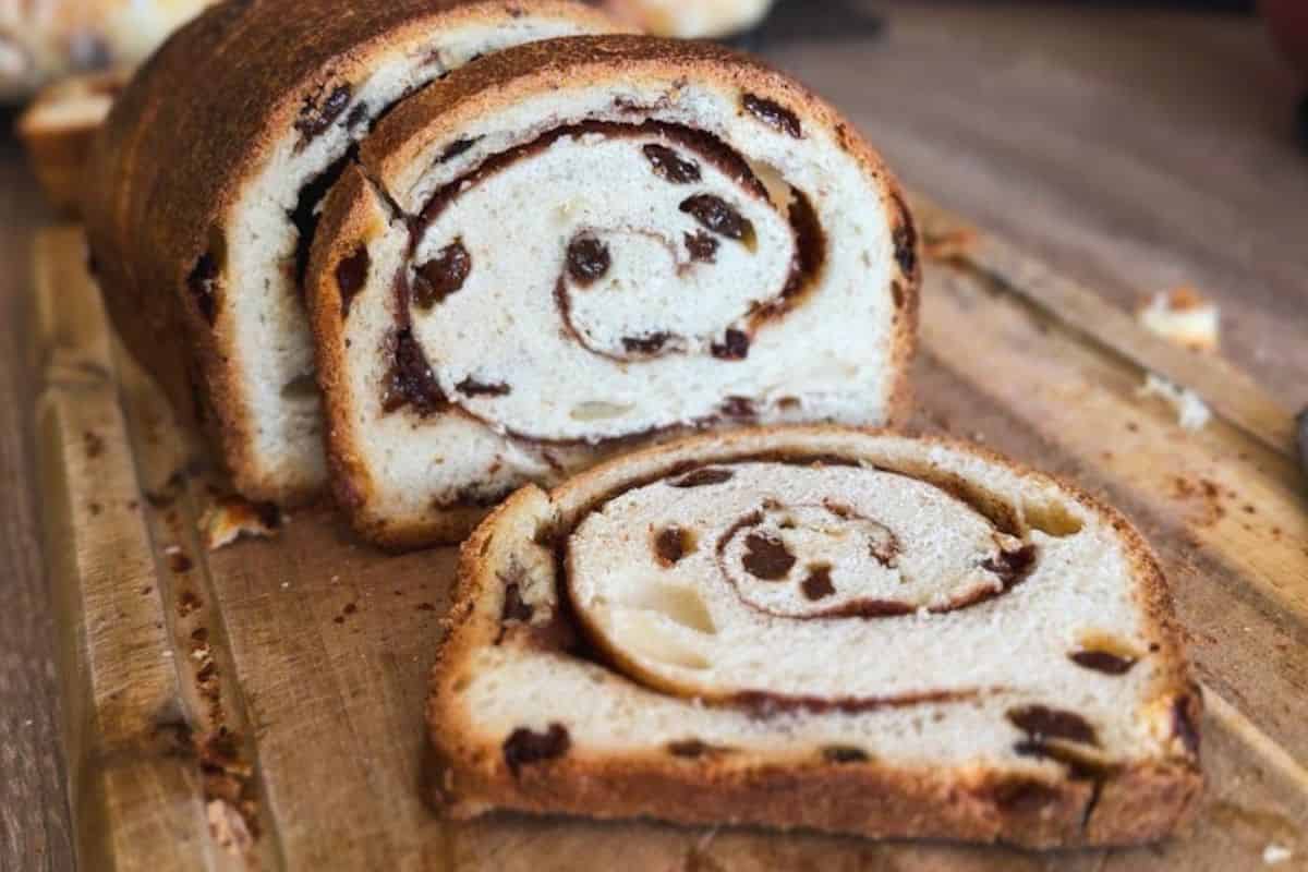 Freshly baked chocolate swirl bread sliced on a wooden surface, showcasing soft interior and rich ch.
