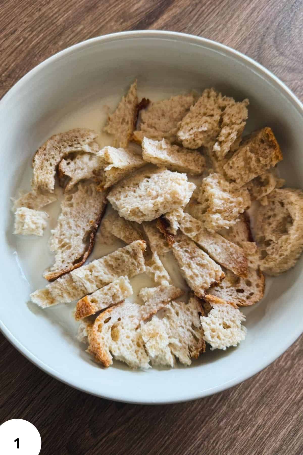 Stale bread pieces soaked in milk for traditional German Hackbraten preparation.
