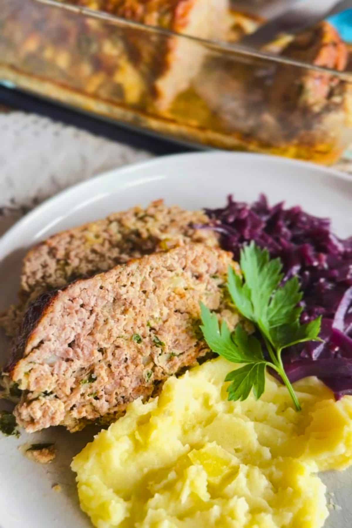 German Hackbraten with mashed potatoes and red cabbage on a white plate.