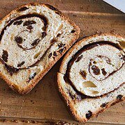 Close-up of cinnamon swirl bread slice with chocolate chips on wooden surface.