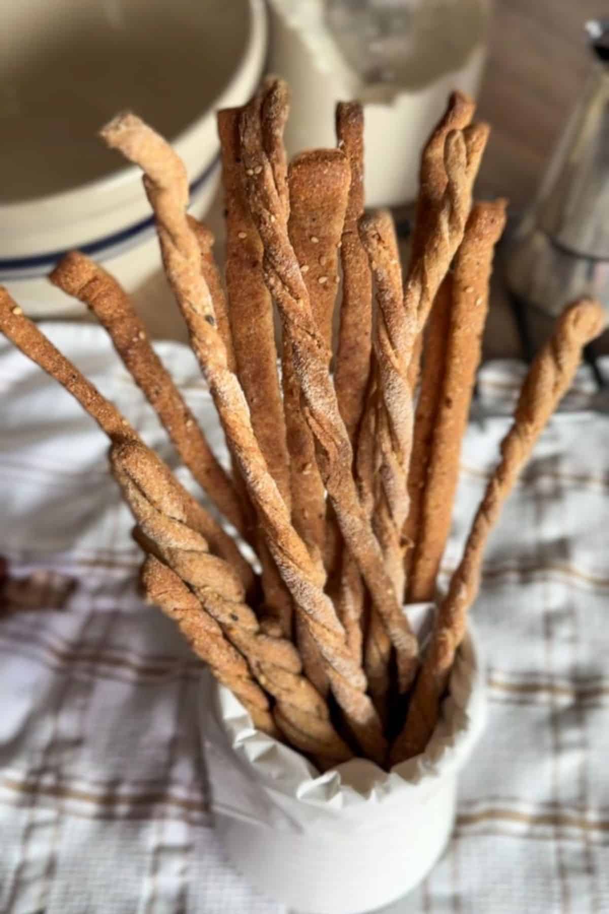 Freshly baked whole grain breadsticks in a white container, crispy and golden brown.