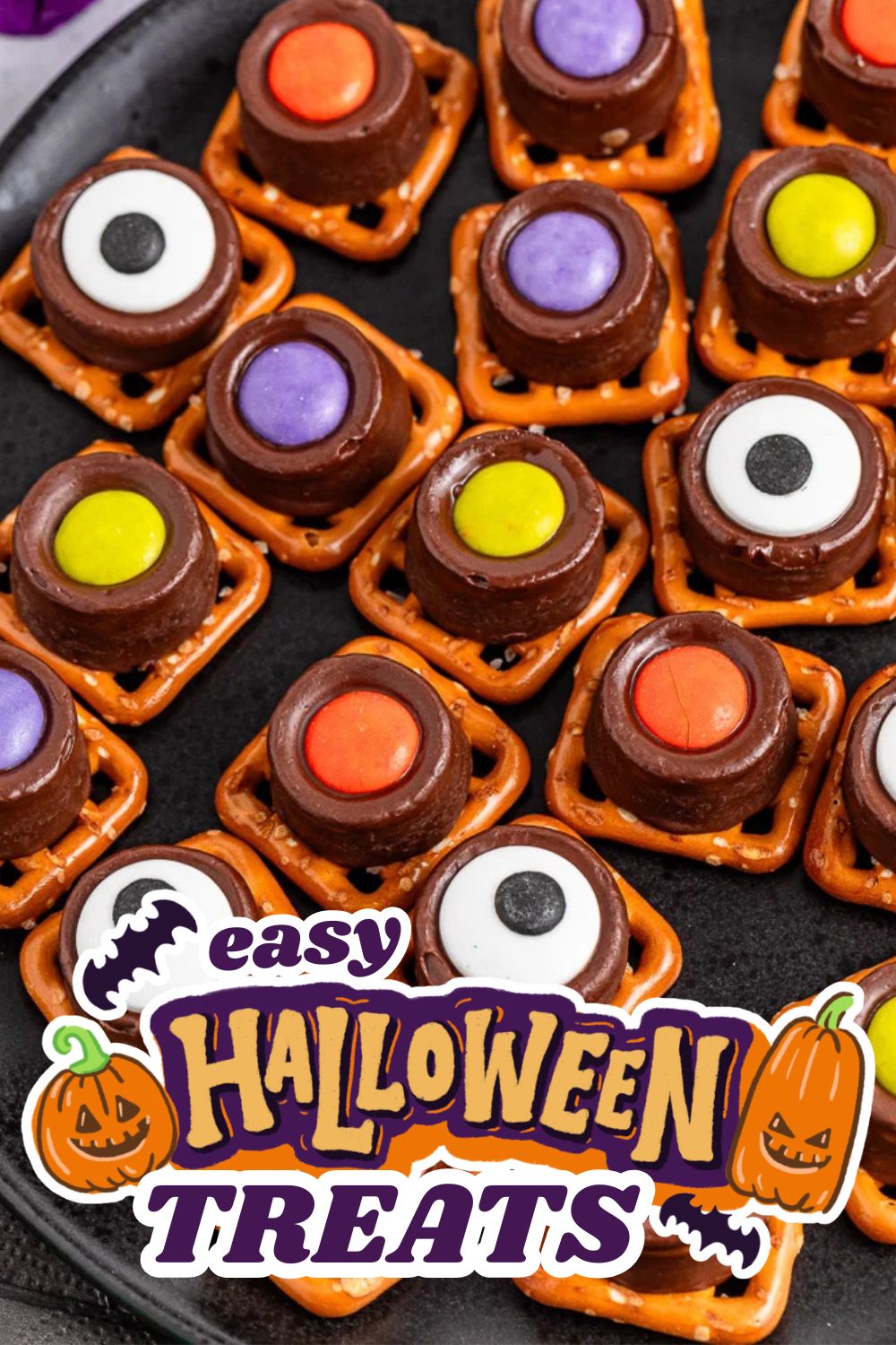 Decorative Halloween treats with colorful candy eyes and chocolate on a black tray.